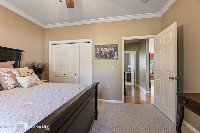 bedroom featuring ceiling fan, a closet, light colored carpet, and ornamental molding