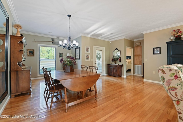 dining space with light hardwood / wood-style floors, an inviting chandelier, and crown molding