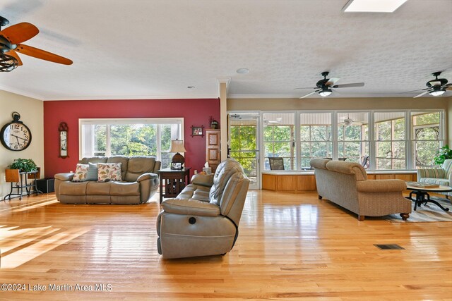 living room with a textured ceiling, light hardwood / wood-style flooring, and crown molding