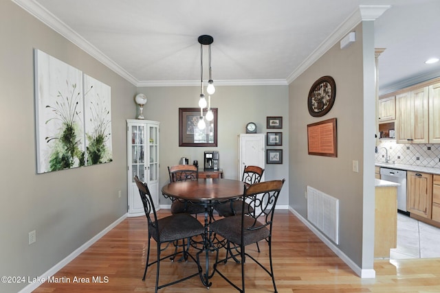 dining room with light wood-type flooring and crown molding