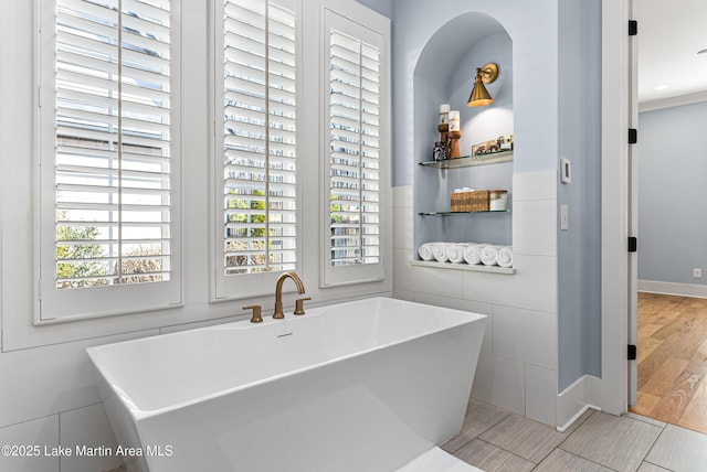 1412 Annalue Dr, Auburn, AL 36830 - bathroom featuring a freestanding bath, baseboards, tile walls, and wood finished floors
