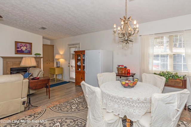 100 Royal Dr, Equality, AL 36026 - dining room featuring visible vents, a textured ceiling, an inviting chandelier, and a tile fireplace