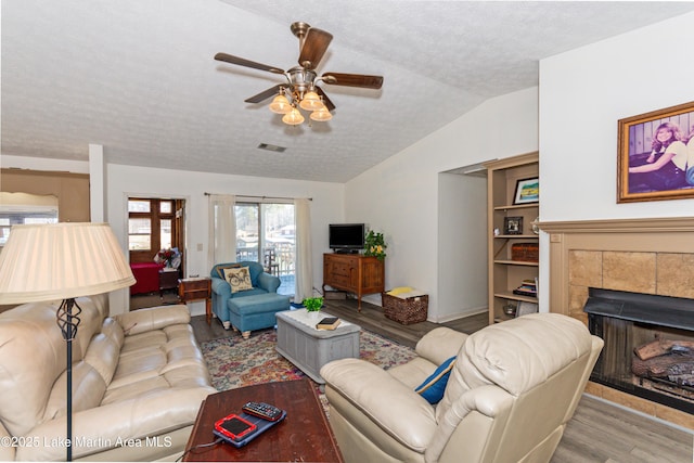 100 Royal Dr, Equality, AL 36026 - living area featuring a textured ceiling, wood finished floors, a fireplace, lofted ceiling, and ceiling fan