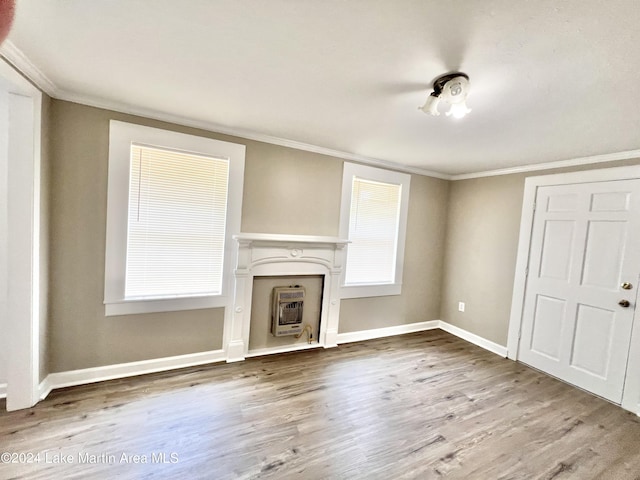 unfurnished living room with heating unit, crown molding, and hardwood / wood-style floors