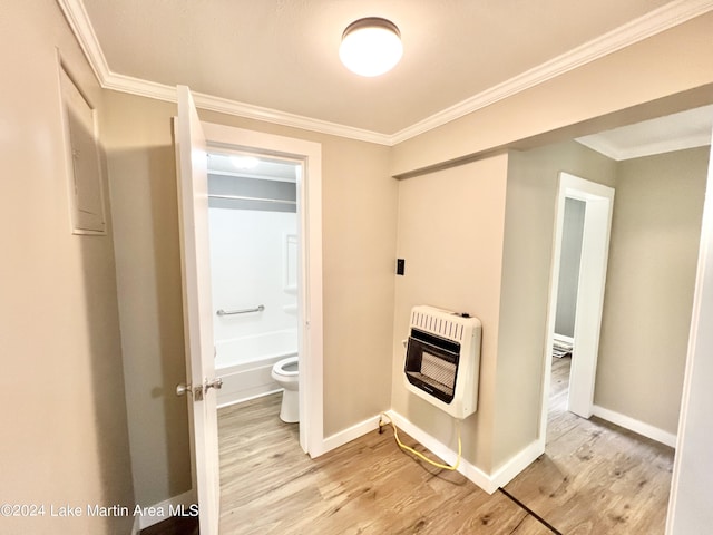 hall with heating unit, crown molding, and light hardwood / wood-style floors