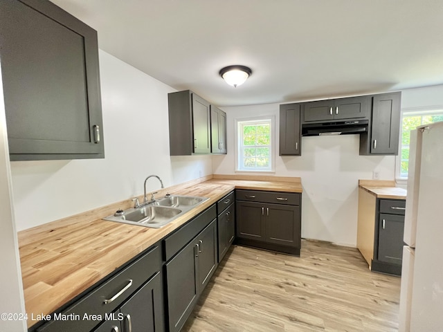 kitchen with butcher block countertops, white refrigerator, light hardwood / wood-style floors, and sink