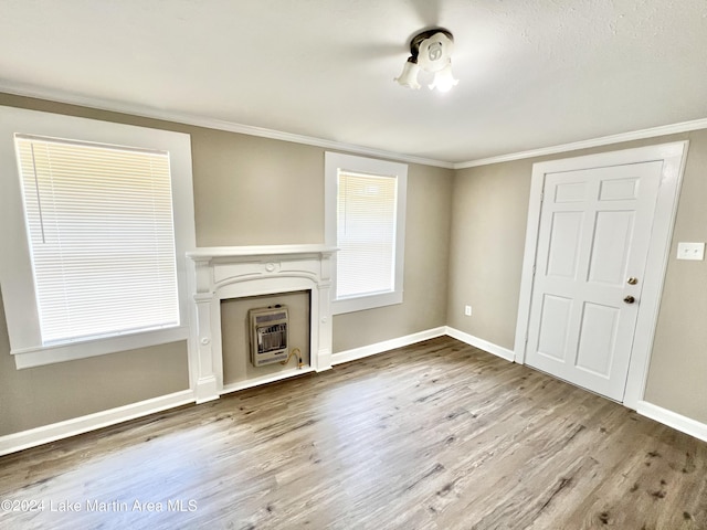 unfurnished living room featuring heating unit, light hardwood / wood-style flooring, and ornamental molding