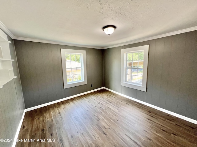 empty room with hardwood / wood-style floors, crown molding, and a healthy amount of sunlight