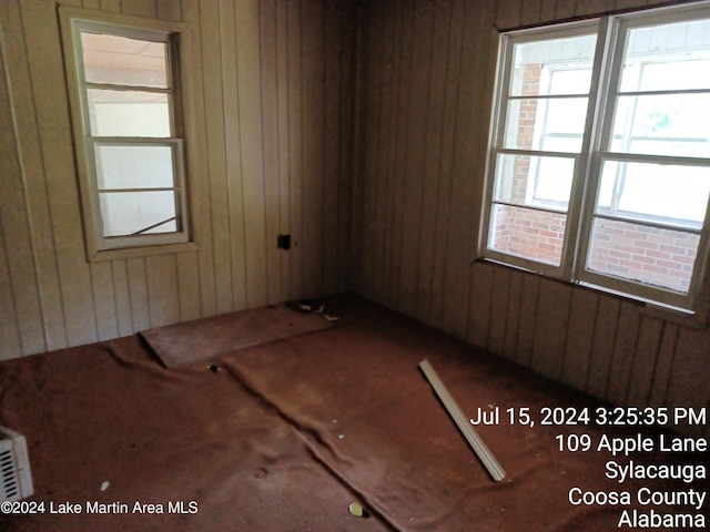 unfurnished room featuring wooden walls