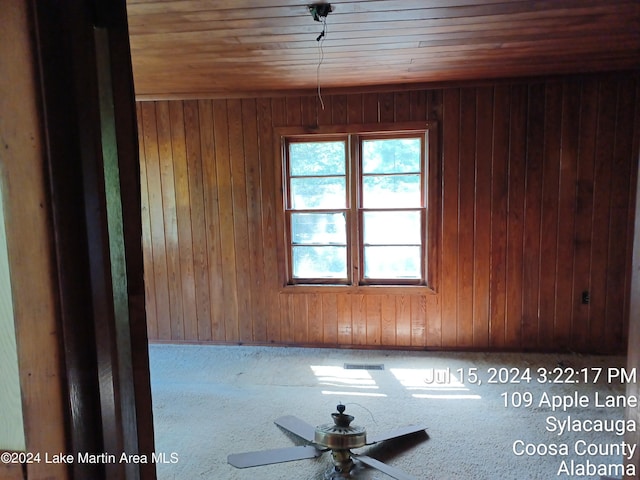 spare room with wood walls, ceiling fan, and wooden ceiling