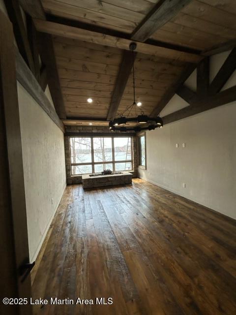 empty room with lofted ceiling with beams, wooden ceiling, and wood-type flooring