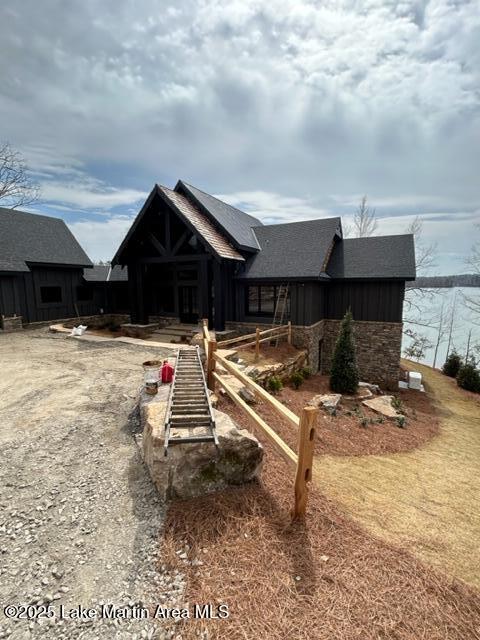 back of house featuring board and batten siding and stone siding