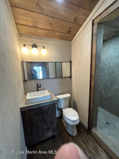 bathroom featuring a walk in shower, toilet, wood finished floors, wood ceiling, and vanity