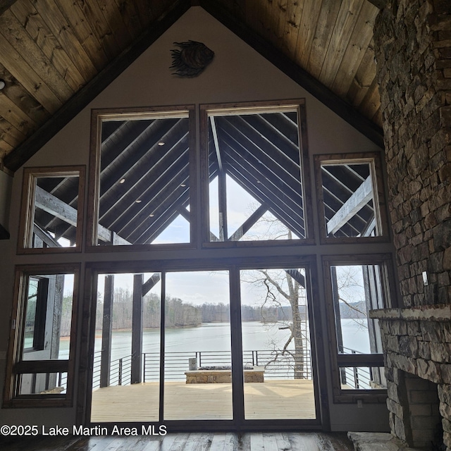 entryway featuring high vaulted ceiling, a water view, a fireplace, and wood ceiling