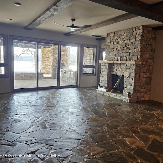 unfurnished living room with ceiling fan, plenty of natural light, a fireplace, and beam ceiling