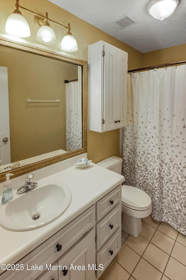 bathroom with toilet, vanity, tile patterned floors, and a textured ceiling