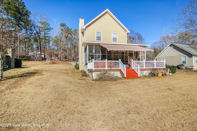 rear view of house with a lawn, a deck, and a sunroom