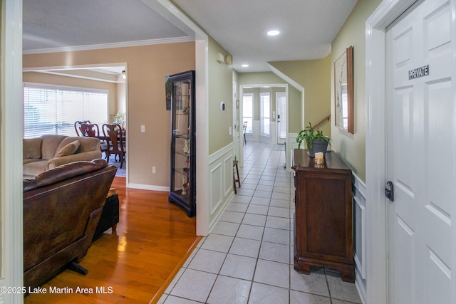 corridor featuring light tile patterned floors, french doors, a wealth of natural light, and crown molding