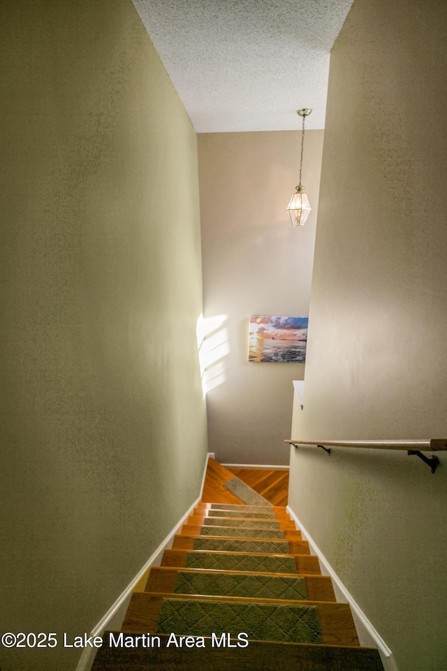 stairs with wood-type flooring and a textured ceiling