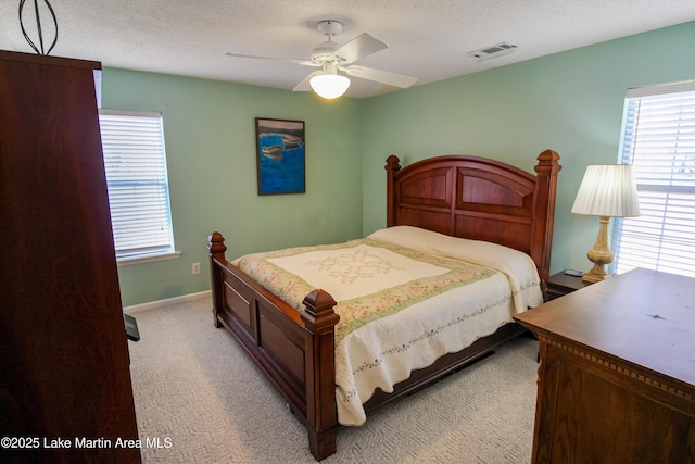 bedroom with ceiling fan, light carpet, and a textured ceiling