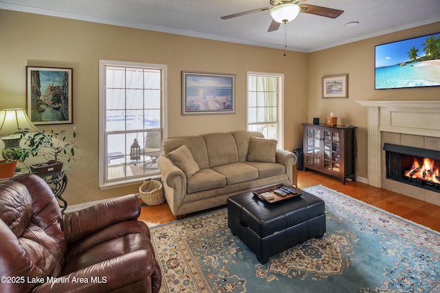 living room featuring ceiling fan, ornamental molding, hardwood / wood-style floors, and a tile fireplace