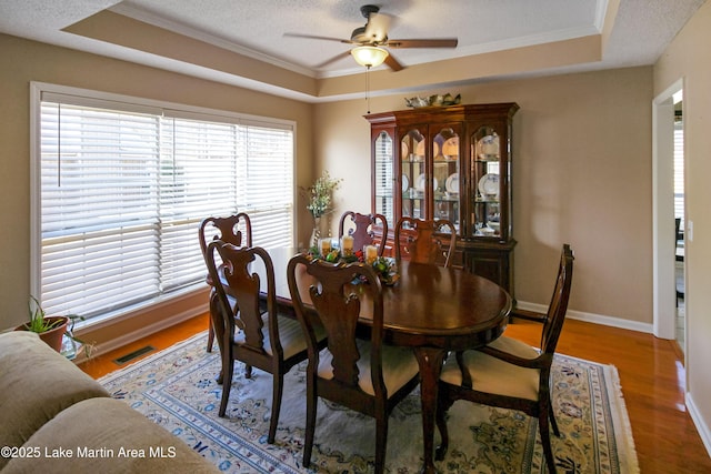 dining room featuring a raised ceiling, ceiling fan, ornamental molding, and hardwood / wood-style floors