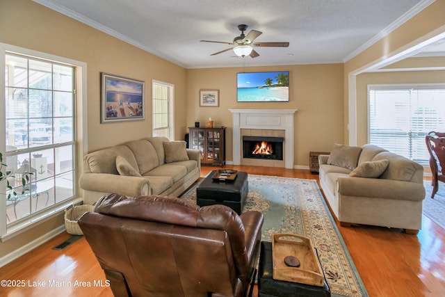 living room with light wood-type flooring, ceiling fan, plenty of natural light, and a tile fireplace