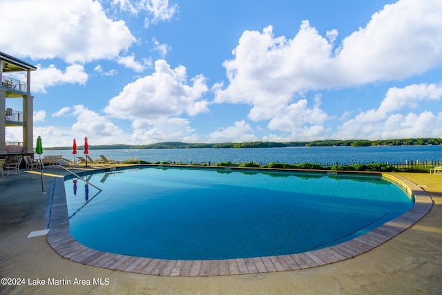 view of pool featuring a water view and a patio