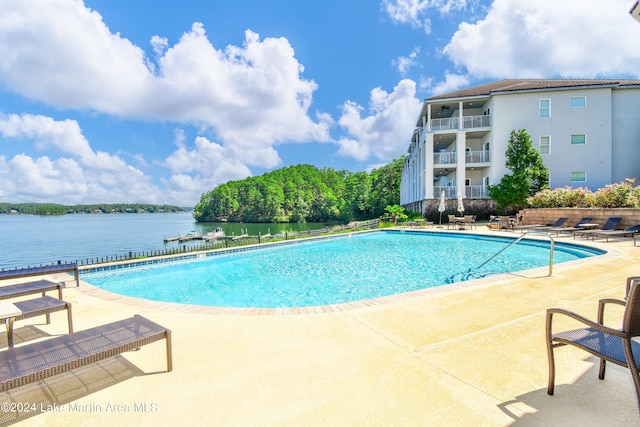 view of swimming pool featuring a water view and a patio