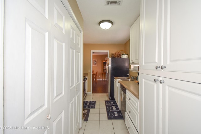 kitchen featuring light tile patterned floors, visible vents, white cabinets, and dishwasher