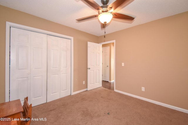 unfurnished bedroom with a ceiling fan, carpet, a closet, and baseboards