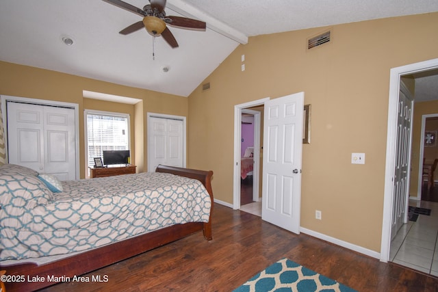 bedroom with visible vents, multiple closets, beamed ceiling, wood finished floors, and baseboards