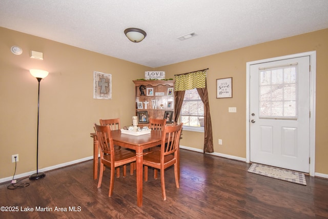 dining area featuring wood finished floors, visible vents, and a textured ceiling