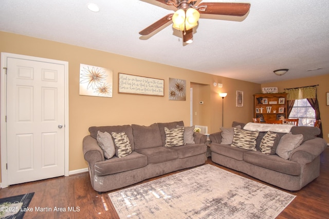 living area featuring ceiling fan, dark wood-style floors, baseboards, and a textured ceiling