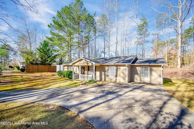 ranch-style house featuring a porch, fence, a front lawn, and driveway