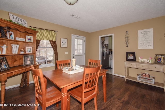 dining space with dark wood-style floors, visible vents, a textured ceiling, and baseboards