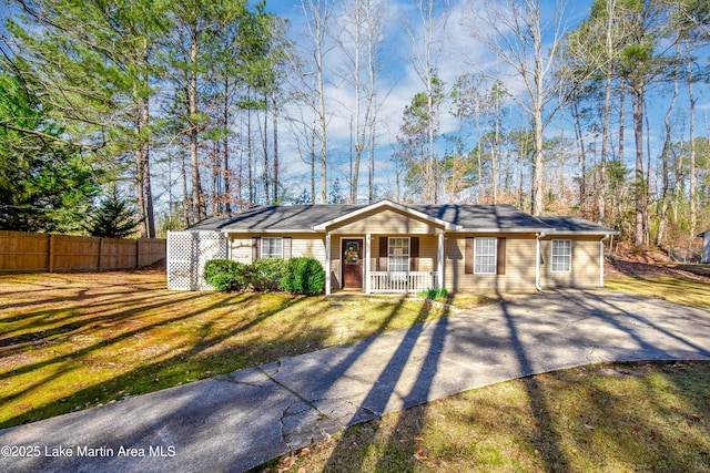 ranch-style home with covered porch, a front lawn, and fence