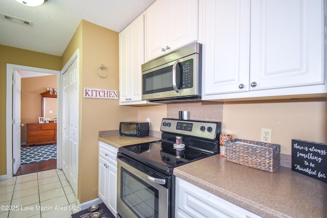 kitchen featuring visible vents, a textured ceiling, white cabinetry, appliances with stainless steel finishes, and light tile patterned floors