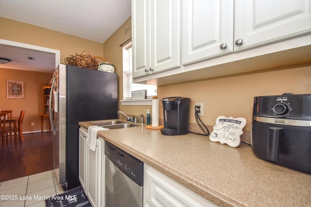 kitchen featuring a sink, light countertops, white cabinets, appliances with stainless steel finishes, and tile patterned floors