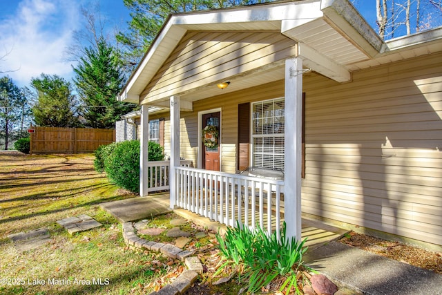 entrance to property featuring covered porch and fence