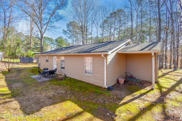 rear view of property with roof with shingles and a patio area