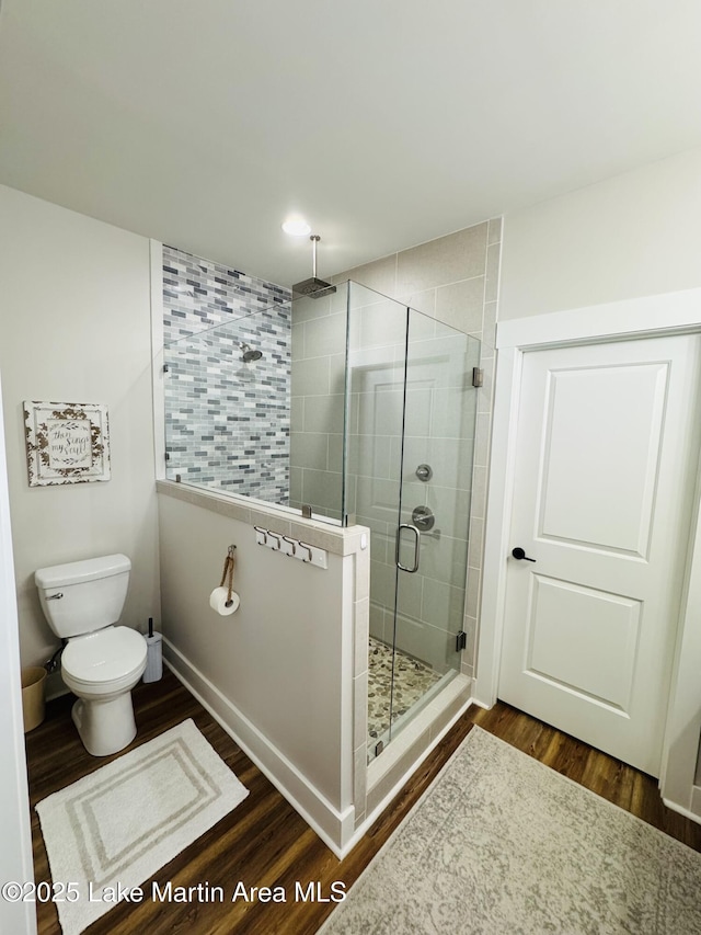 bathroom with hardwood / wood-style flooring, toilet, and walk in shower