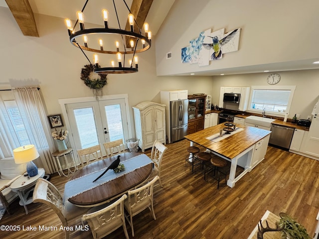 dining room with french doors, dark wood-type flooring, sink, a chandelier, and high vaulted ceiling