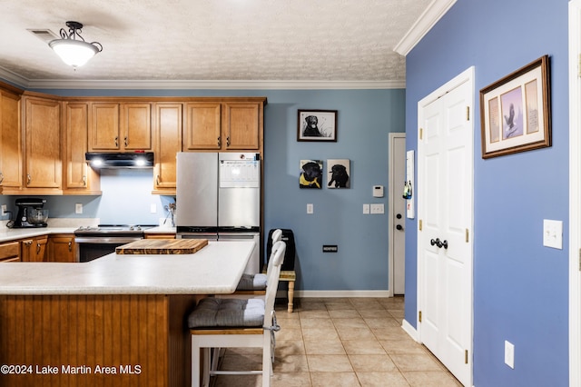 kitchen with a kitchen breakfast bar, light tile patterned floors, ornamental molding, a textured ceiling, and appliances with stainless steel finishes