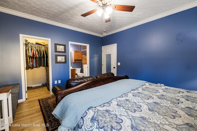 bedroom featuring ceiling fan, light wood-type flooring, a spacious closet, ornamental molding, and a closet