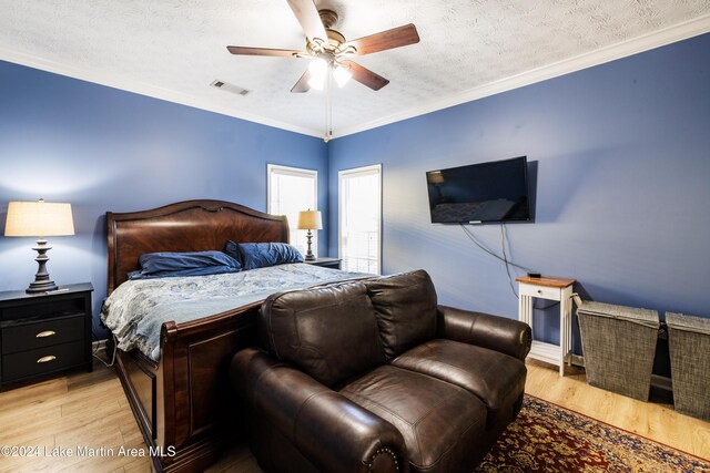 bedroom with a textured ceiling, light wood-type flooring, ceiling fan, and crown molding