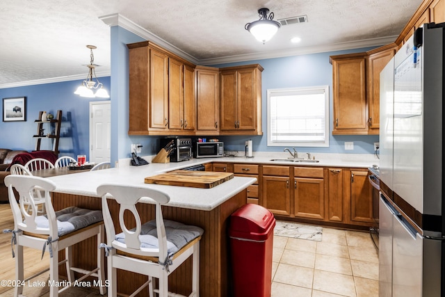 kitchen with pendant lighting, sink, crown molding, appliances with stainless steel finishes, and a kitchen bar