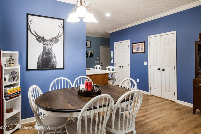 dining room featuring an inviting chandelier, ornamental molding, a textured ceiling, and light hardwood / wood-style flooring