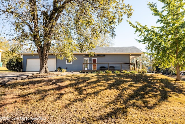 ranch-style home featuring a garage, a wooden deck, and a front lawn