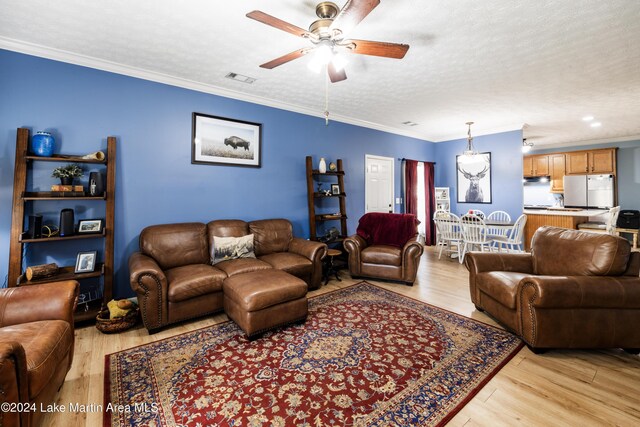 living room with a textured ceiling, ceiling fan, light hardwood / wood-style floors, and crown molding